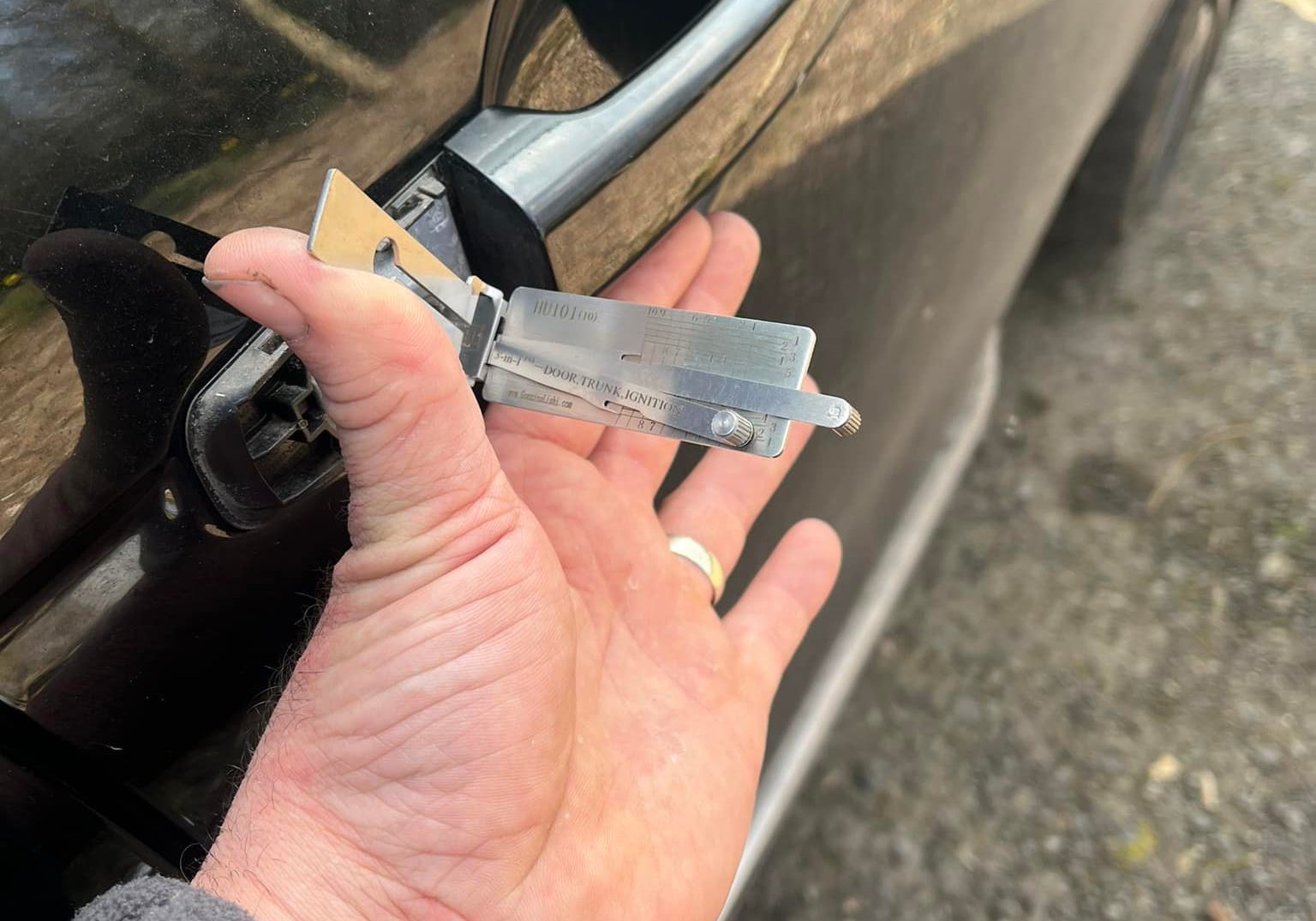 Mechanic using a lock picking tool to unlock a black car